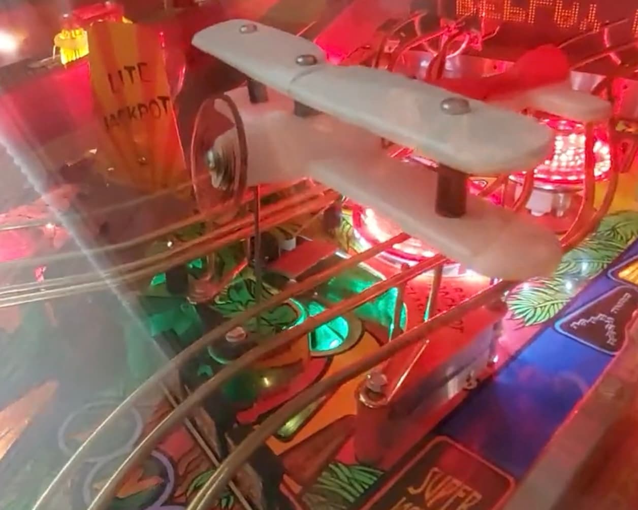 Iconic Indiana Jones little white biplane set above the glowing lights of a pinball game for sale play field.